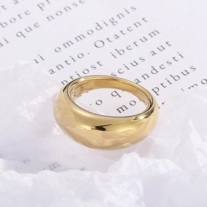 Macro shot of minimalist wide gold band ring on vintage white paper with text