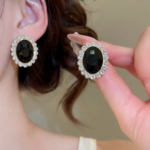 Close-up of vintage oval stud earrings featuring black stone centers and zircon halos