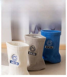 Detail of ribbed knit socks featuring embroidered happy face patch and NICE lettering