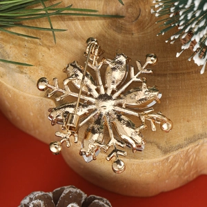 Back view of a gold snowflake brooch with secure pin buckle and sparkling rhinestones