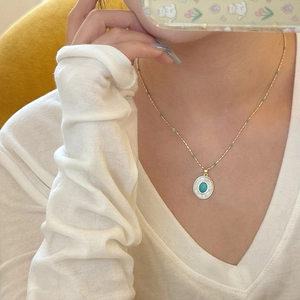 Gros plan du collier vintage en or avec pendentif ovale turquoise et zircons brillants