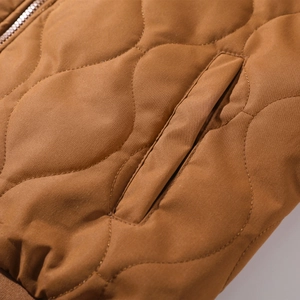 Macro view of brown quilted jacket featuring gourd stitching and diagonal side pocket