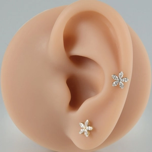G23 titanium flower labret stud with white zircon crystals shown on a model ear