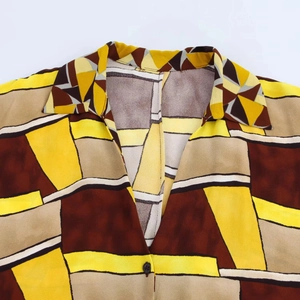 Dettaglio del colletto della camicia con motivi geometrici gialli e marroni e bottoni neri