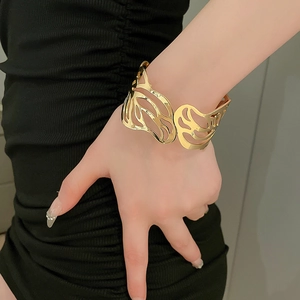 Close-up of golden hollow metal open cuff bracelet with abstract carved pattern on wrist