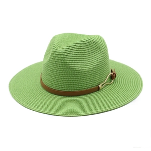 Detailed shot of green woven straw fedora hat with brown leather band and gold buckle