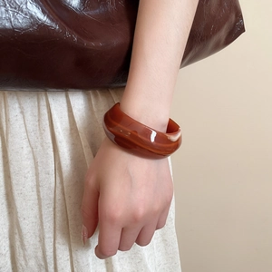 Close-up of wide tortoiseshell acrylic bangle with vintage marbled texture and glossy finish