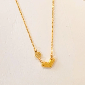 Detail of gold titanium steel heart pendant and hollow ring on a fine necklace chain