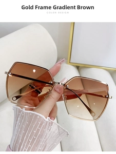 Detail of oversized gold-framed sunglasses with brown gradient lenses and screw accents