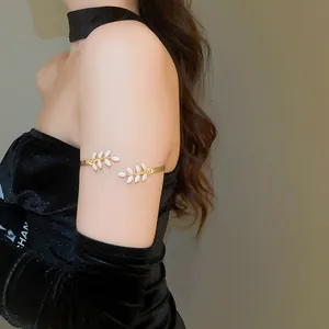 Close-up of golden leaf arm cuff with white enamel details worn on the upper arm
