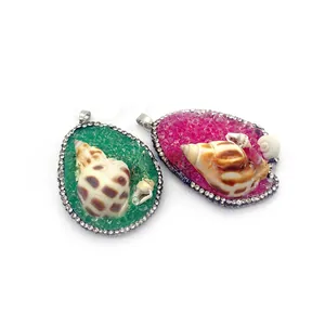 Detailed view of conch shell pendants with rhinestones in green and rose pink bases