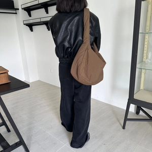 Rear view of model wearing a large brown puffer tote bag with a soft quilted texture