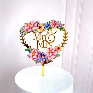 Detail of heart-shaped acrylic cake topper with golden Mr & Mrs and floral design