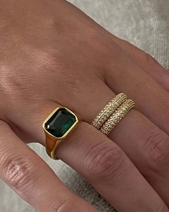 Macro shot of gold emerald cut green stone signet ring with stacked eternity diamond bands