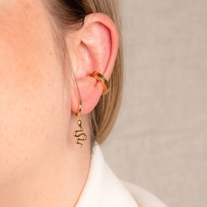 Detailed close-up of model wearing gold snake pendant earrings and a minimalist ear cuff