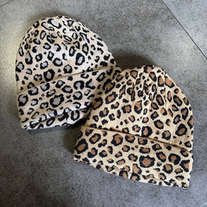 Detailed view of leopard print knit beanies in beige and khaki with soft ribbed texture