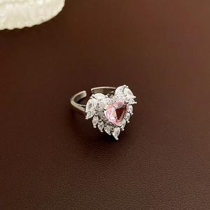 Detail of pink heart-shaped crystal ring with white zircon wings on leather background