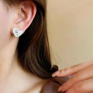 Primo piano dell'orecchino a cuore con tulipani e perle indossato da una modella