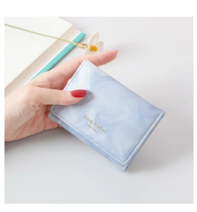 Detail of light blue marble pattern wallet with gold foil text in model's hand