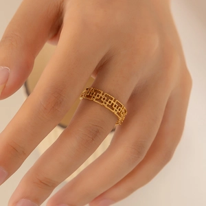 Detail of gold titanium ring with hollow geometric pattern on a model's finger