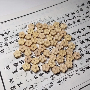 Perles de buis naturel en forme de fleur pour bijoux DIY sur fond de calligraphie