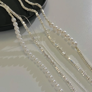 Detail of silver faceted beads, fine snake chains and white pearls in minimalist layout