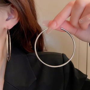 Detail shot of large silver hoop earrings showing size scale and metallic finish