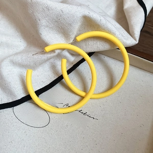 Detailed close-up of yellow round acrylic earrings on a rustic wooden jewelry display