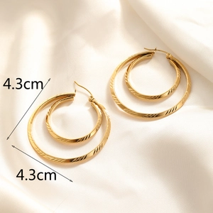Macro shot of gold-plated hoop earrings featuring a 4.3cm diameter with textured engraving
