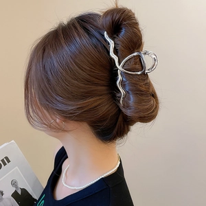 Close-up of a silver irregular wave metal hair claw clip worn in a modern hairstyle