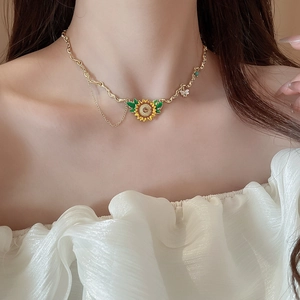 Detail view of sunflower and bee necklace with gold chain worn on a model's neck