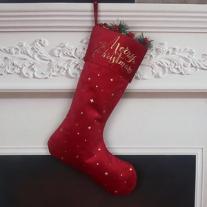 Red velvet Christmas stocking with gold stars and Merry Christmas embroidery on fireplace