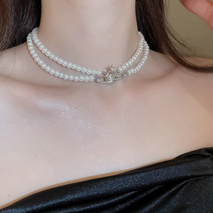 Detailed view of a double-layer pearl choker with a crystal-encrusted Saturn pendant