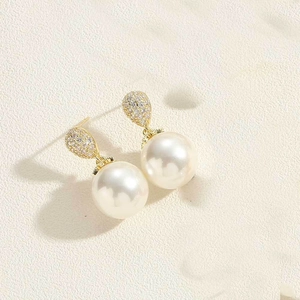 Detail of 14K gold drop-shaped earrings with white pearls and sparkling zircon accents