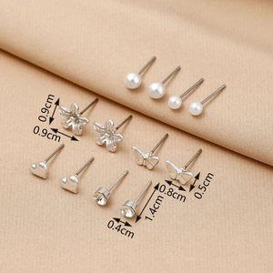 Detailed view of pearl and silver stud earrings set with size measurements on fabric
