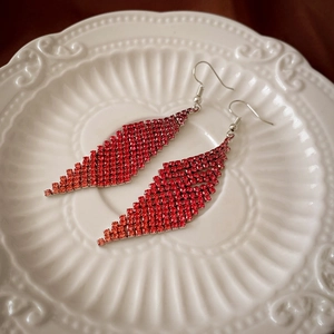 Gros plan de boucles d'oreilles à franges en strass rouges sur un plateau en porcelaine