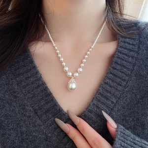 Gros plan d'un collier doré élégant avec pendentif perle blanche porté par un mannequin