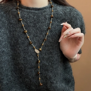 Macro detail of bead necklace with zircon leaf pendant on grey sweater model view