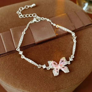 Bracelet papillon argenté avec pierres roses en forme de goutte sur velours brun