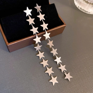 Detailed close-up of silver star tassel earrings with brushed metal finish and long chains