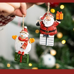 Close-up of handmade Santa and Snowman hanging ornaments with festive bokeh background