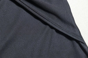 Detailed close-up of high-density black fabric stitching and pleated texture on the dress