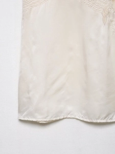 Detailaufnahme des elfenbeinfarbenen Spitzen-Dessous-Tops mit glatter Satin-Textur