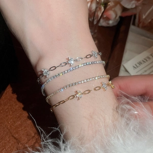 Detailed view of layered 18k gold plated bracelets with zircon butterflies and tennis chains