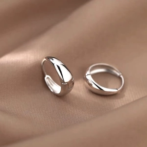 Gros plan de boucles d'oreilles goutte argentées sur un fond de soie kaki doux