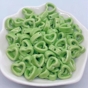 Macro view of green heart-shaped ceramic beads with ink wash pattern in a white bowl