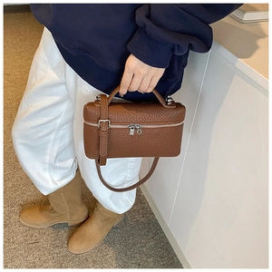 Detail of a brown lychee pattern leather box bag with silver zipper and top handle