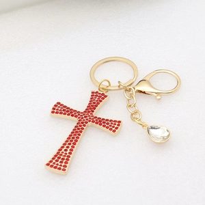 Detail of a gold cross keychain with red rhinestones and clear crystal teardrop charm