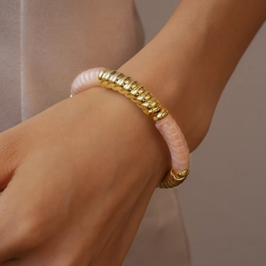 Gros plan détaillé du bracelet géométrique doré et rose avec texture nervurée au poignet