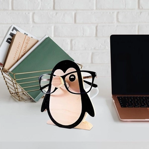Detail view of a penguin-shaped wooden glasses holder stand on a bright office desk